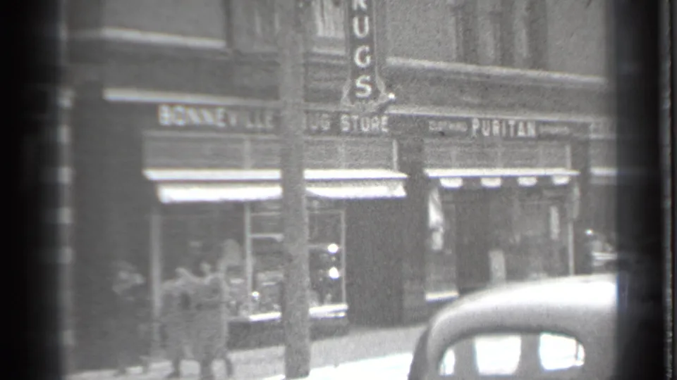 Danielson, Connecticut storefront row with the RUGS sign, Bonneville Drug Store, pedestrians, awnings, and a vintage car in front.