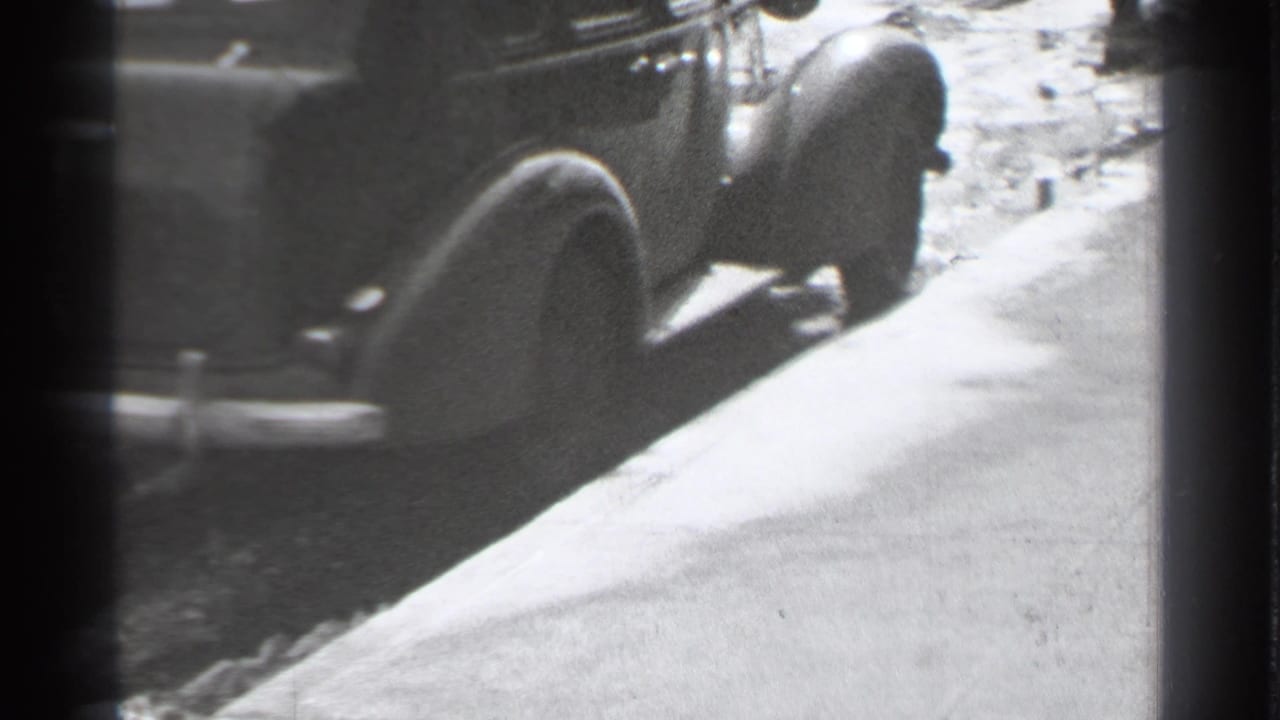 Sidewalk beside parked cars with a pedestrian partly visible.
