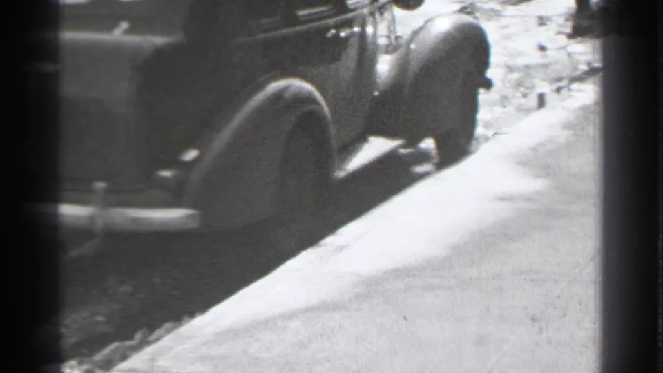 Danielson sidewalk scene with a rounded parked car and a partially visible pedestrian passing through the frame.