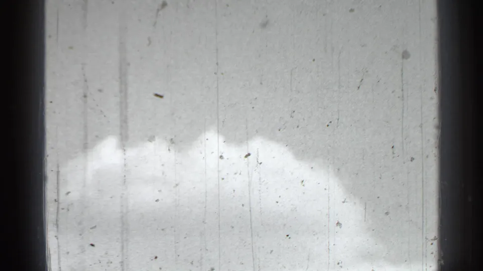 Bright sky and clouds appear in a 1939 New York home-movie frame with dust, scratches, and dark film edges visible.