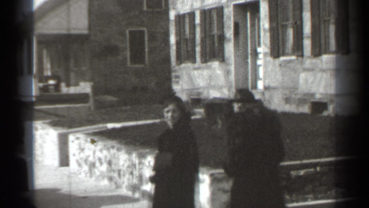 Two women in 1930s-style coats and hats walk past stone walls and residential buildings in New York, based on clip metadata.