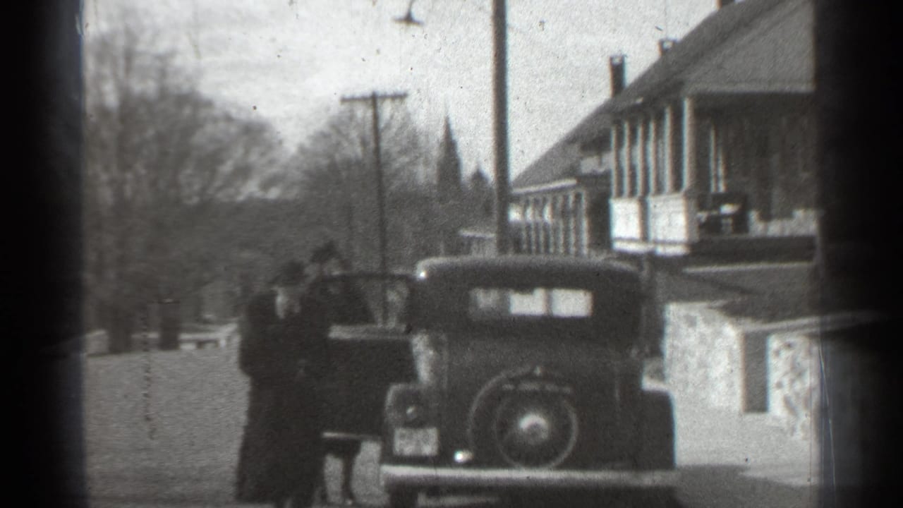Parked older car on a street with an open door and a person nearby.