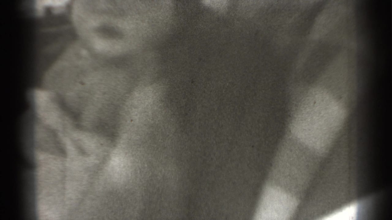 Soft close-up of a young child wearing a light cap, with dark film borders.