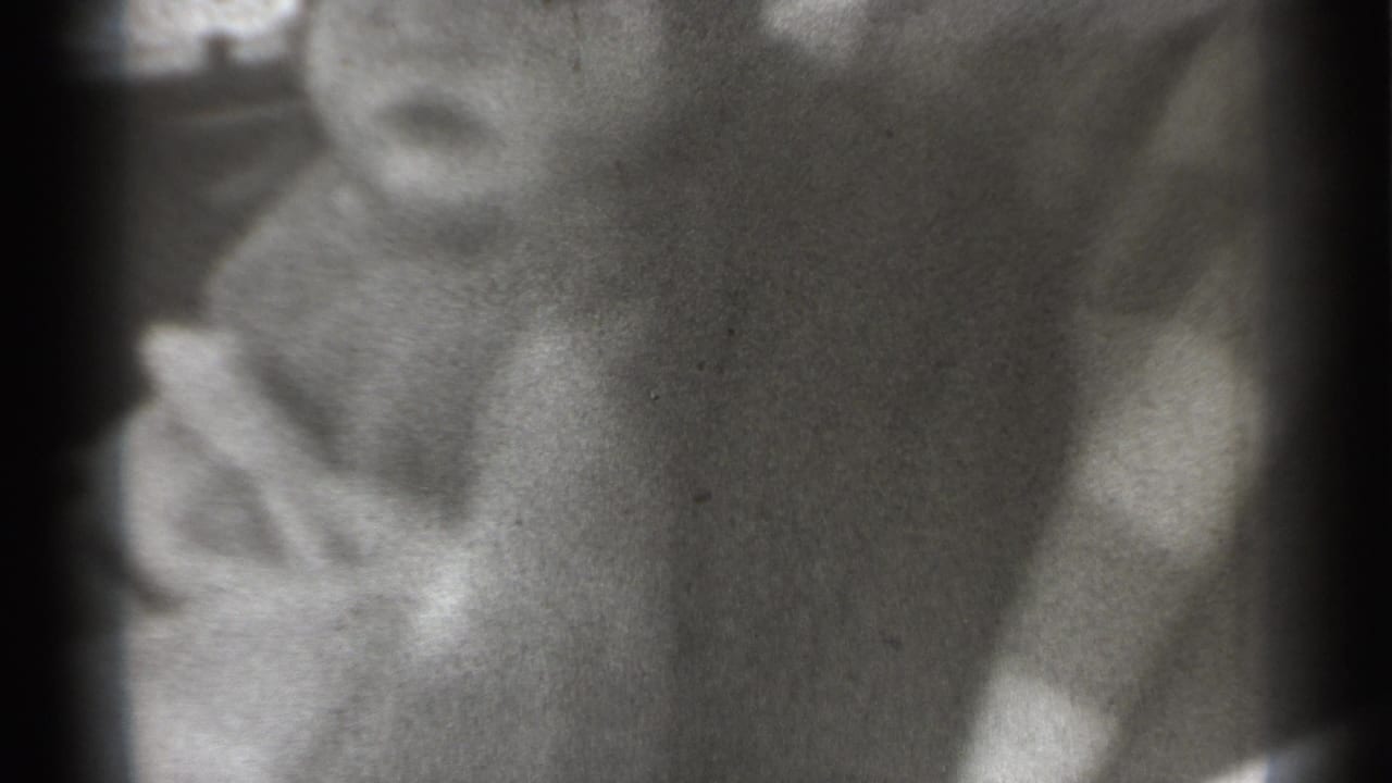 Young child's face partly centered, with a small string-like object near the mouth.