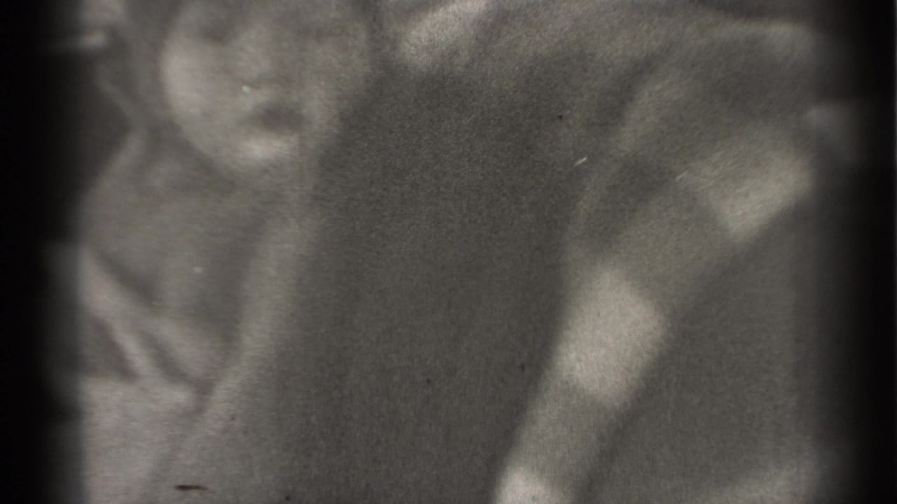 Baby turned partly away, with an adult figure blurred in the background.
