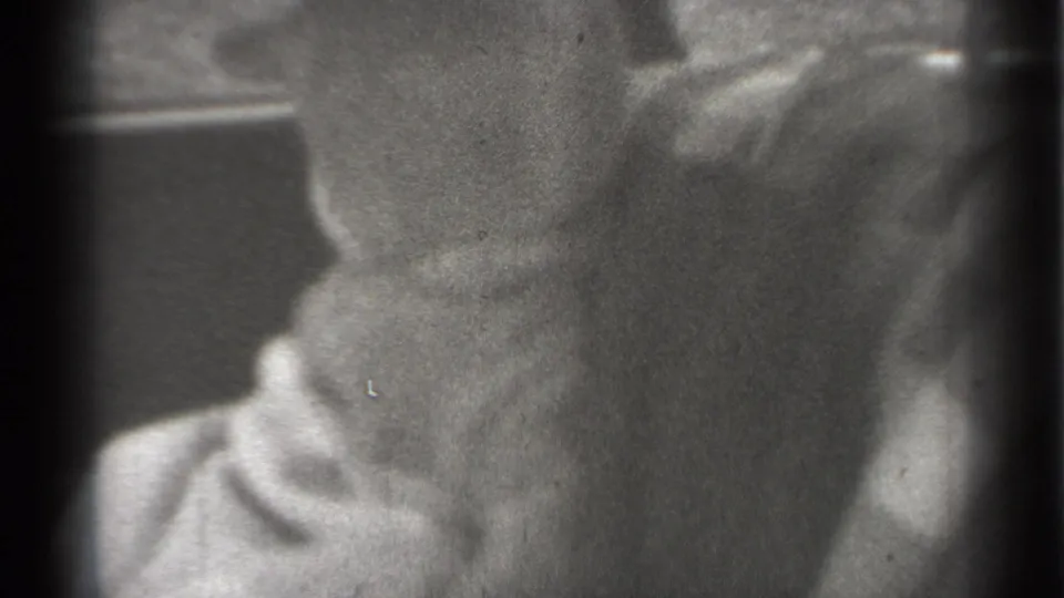 Soft black-and-white 8mm frame from 1939 New York showing a baby in light clothing seated low inside a vintage automobile interior.