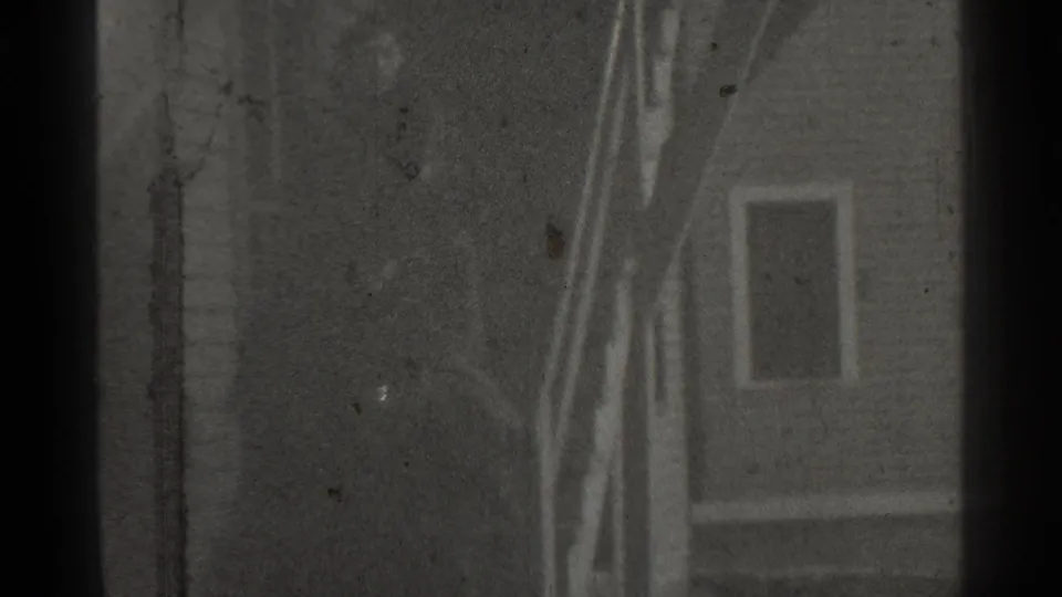 Final 1939 New York frame showing a dark porch or entry area with railings and a distant person-like figure near the doorway.