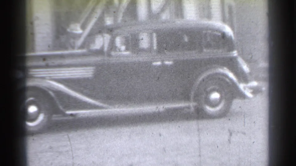 Close side framing of a dark pre-war sedan in a New York alley, with grain, blur, and contact-print borders visible.