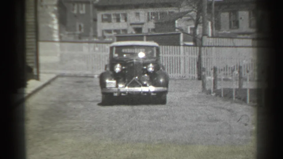 The car reaches a closer front view, showing rounded fenders, bright headlights, and chrome details on the New York street.