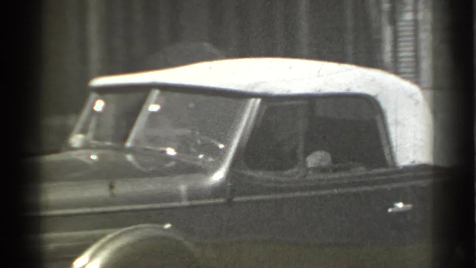 In 1939 New York home-movie footage, a dark convertible with a white soft top is seen from the side as it passes close to the camera.