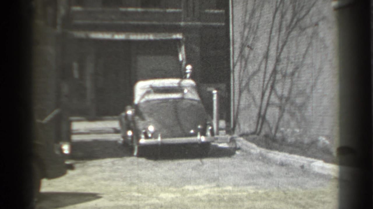 Classic convertible parked at the end of a narrow alley between brick buildings.
