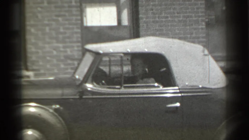 1939 New York 8mm frame showing the side of a classic convertible with a driver visible through the window.