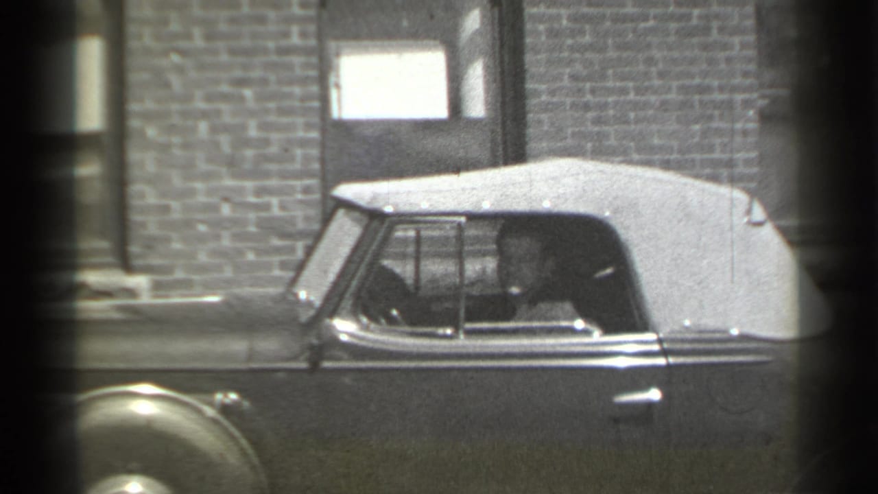 Driver visible through the side window of a parked convertible.