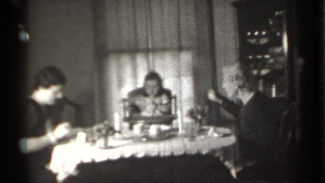 Woman at left eats while a child and older woman sit across the table.