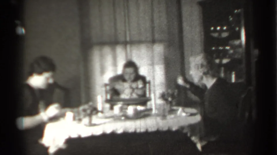 Black-and-white 1939 New York home-movie frame of a woman eating as a child and older woman sit at the same table.