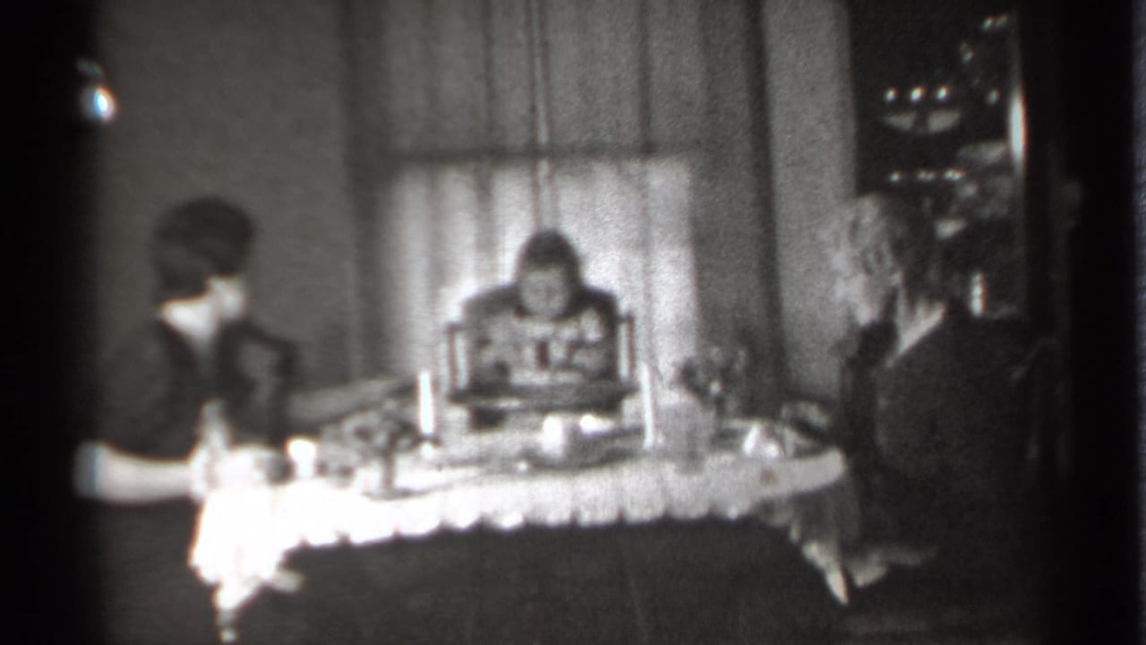 Three people remain seated at a dinner table, with the child centered between the women.