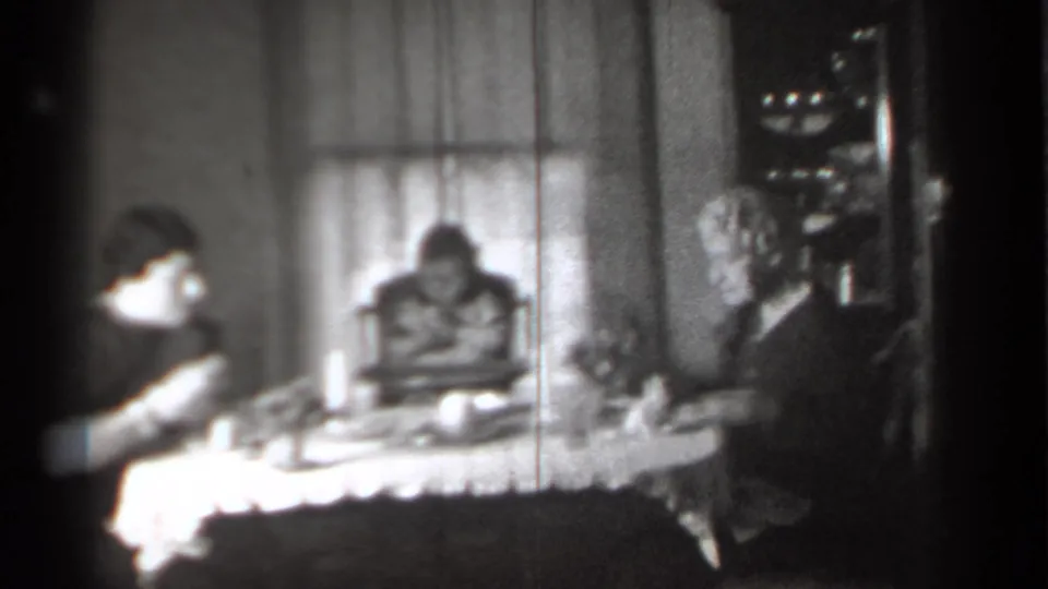 1939 New York interior with adults seated on either side of a child in a high chair at a household meal.