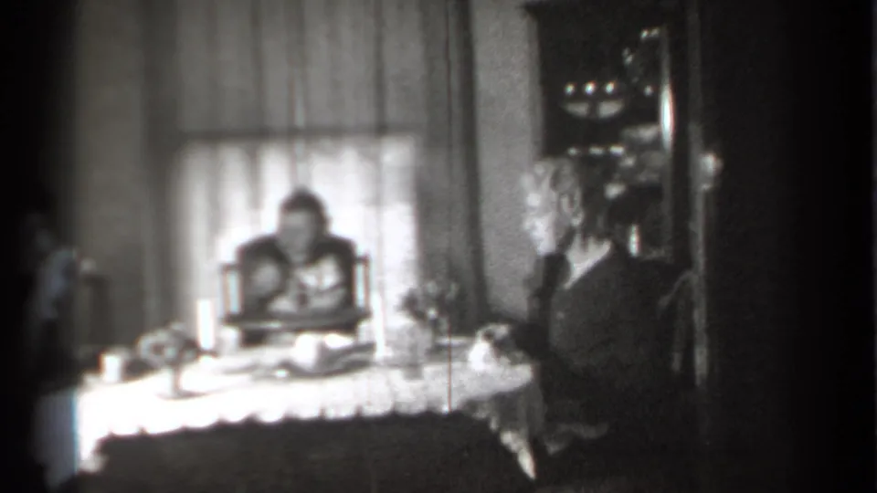 1939 New York home interior showing an adult seated beside a lace-covered table and a child in a high chair.