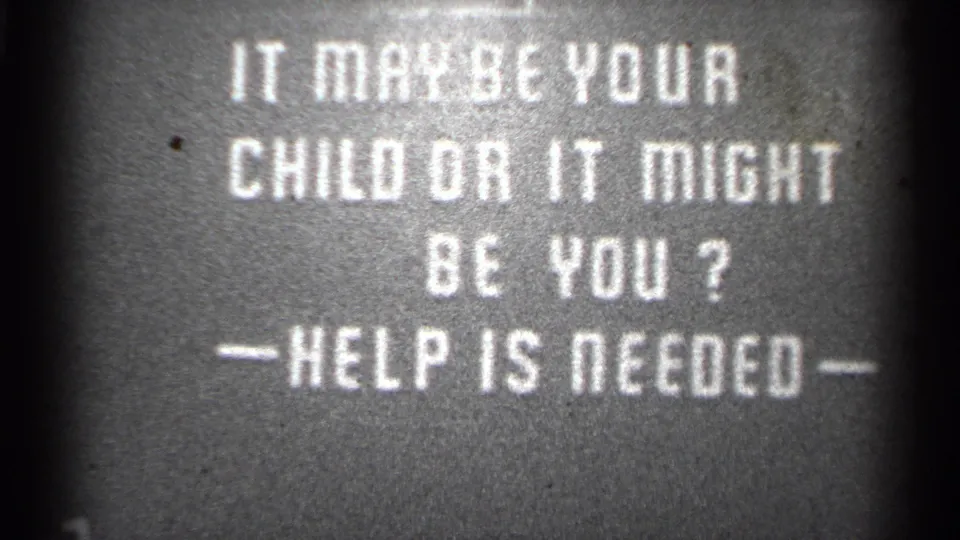 Black-and-white 8mm frame from the San Francisco-listed clip showing the final hold on the help-needed title card.