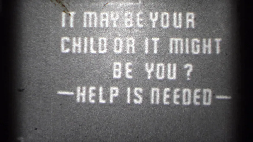 1944 8mm frame with a stark public-service title card asking for help, shown in soft monochrome contrast.