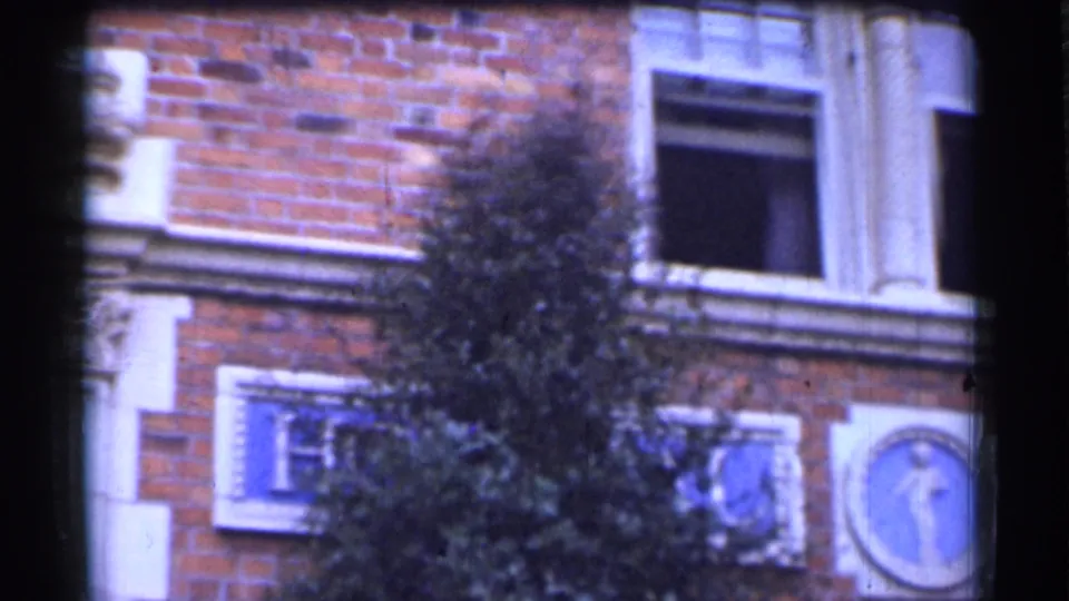 San Francisco 1944 building exterior showing an open window, brickwork, decorative plaques, and a circular emblem near the frame edge.