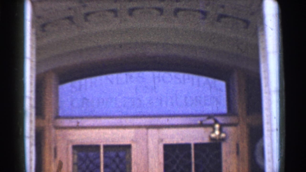 Wooden building entrance with arched transom window and faded lettering.