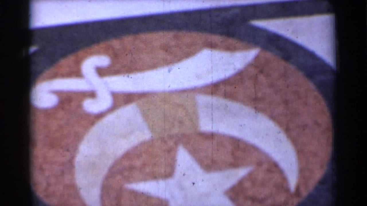 Painted emblem with white sword, crescent shape, and star on a brown surface.