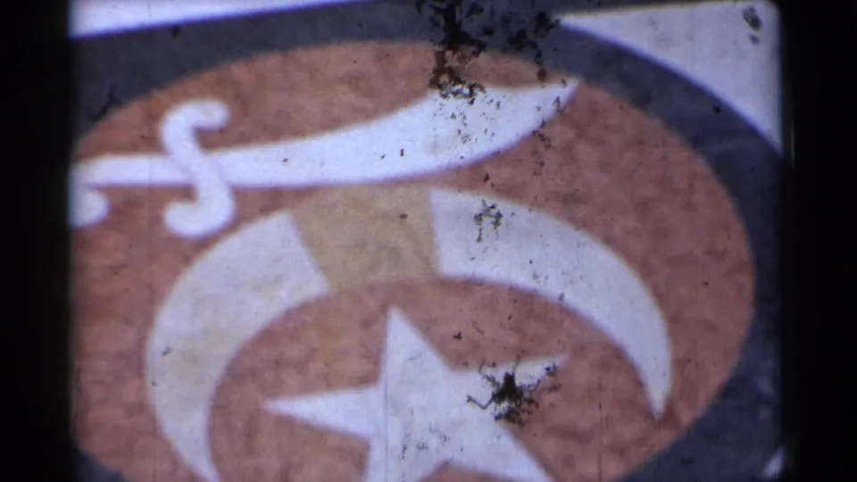 Final 1944 San Francisco frame of the symbolic emblem, showing the sword, crescent, star, and visible surface marks from the film scan.