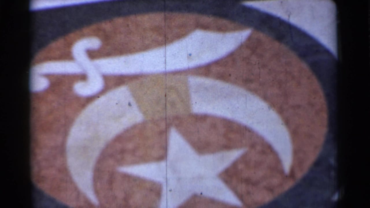 1944 San Francisco 8mm frame showing a close-up of an unidentified emblem with star, crescent, and sword-like shapes.