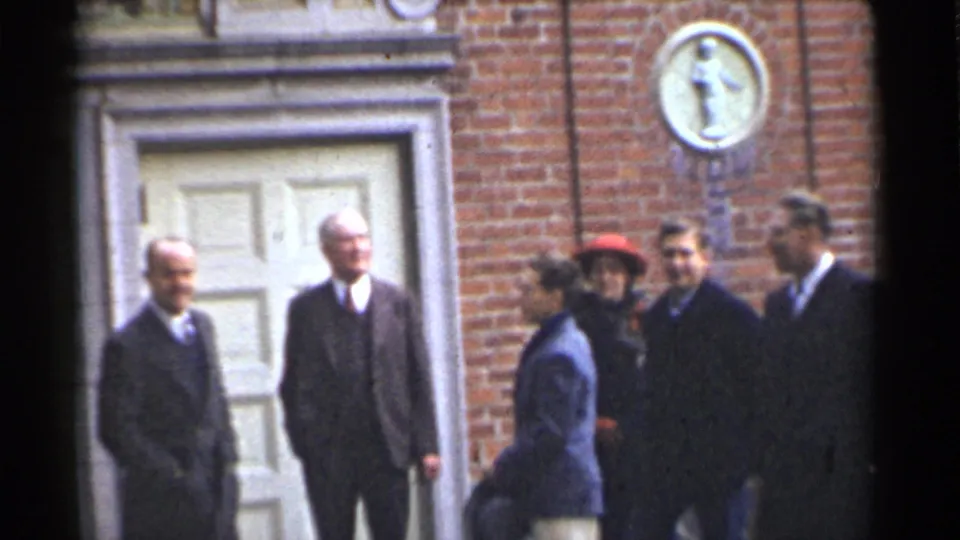 Final 1944 San Francisco frame showing a small adult group outside a brick doorway, with soft 8mm color and grain.