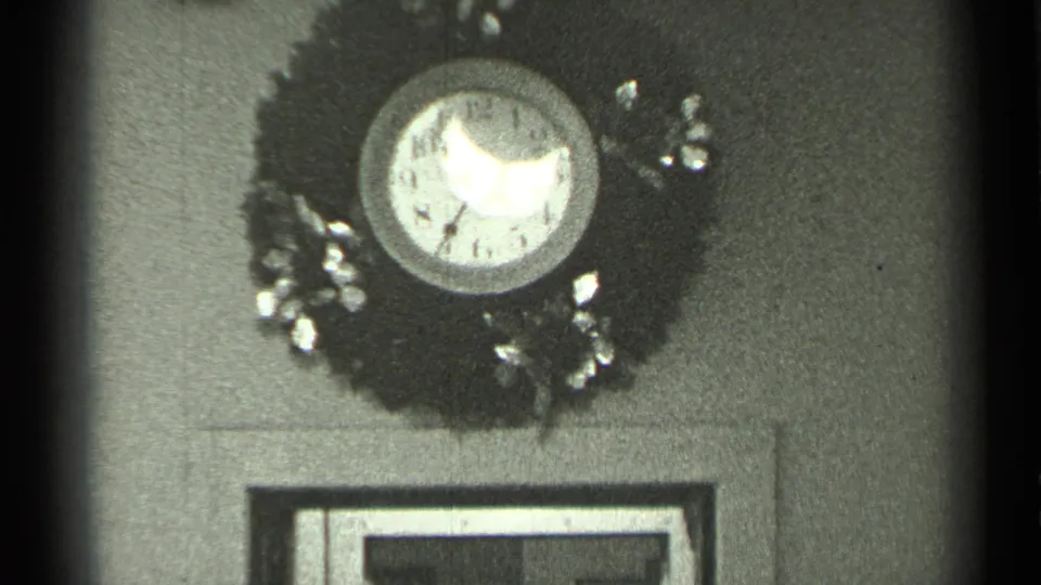 A decorative wall clock, possibly surrounded by a wreath-like ornament, appears above a framed feature in the same interior.