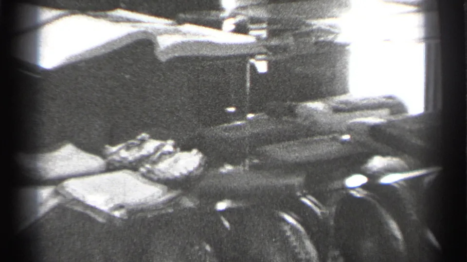 1944 San Francisco home-movie frame of a glass case with folded keepsakes, a doll in a light dress, and a football beside it.