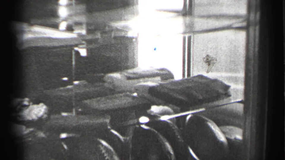Black-and-white 8mm frame from 1944 San Francisco showing a football and folded objects inside a reflective glass case.
