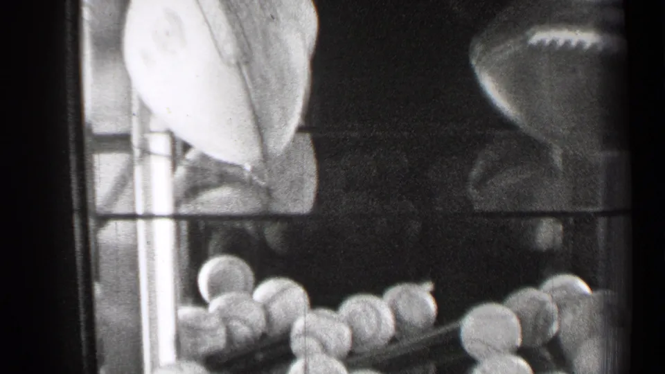The final frame shows baseballs lined along a lower shelf with footballs above and to the side inside the glass case.