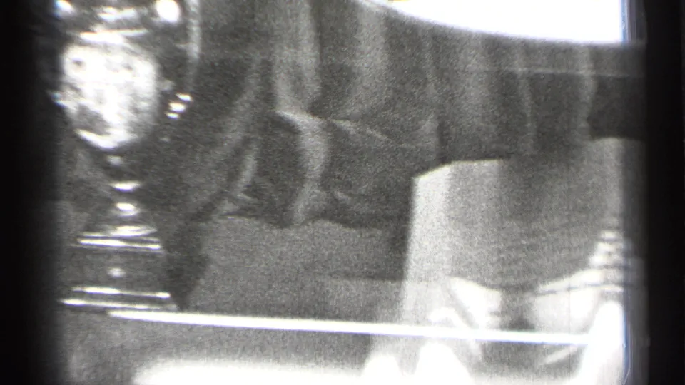 Black-and-white 8mm frame from San Francisco showing a trophy cup and nearby sports display items through reflective glass.