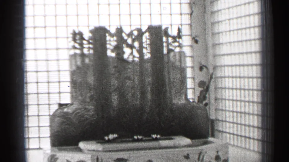 1944 San Francisco frame showing a central sculptural or plant-like feature above a tiled bath, surrounded by glass-block walls and bright light.