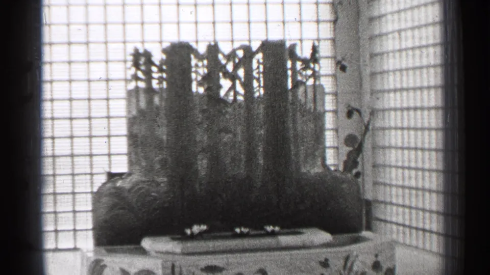 1944 San Francisco 8mm frame showing a shoji-style screen and dark sculptural centerpiece in a Japanese-style interior.