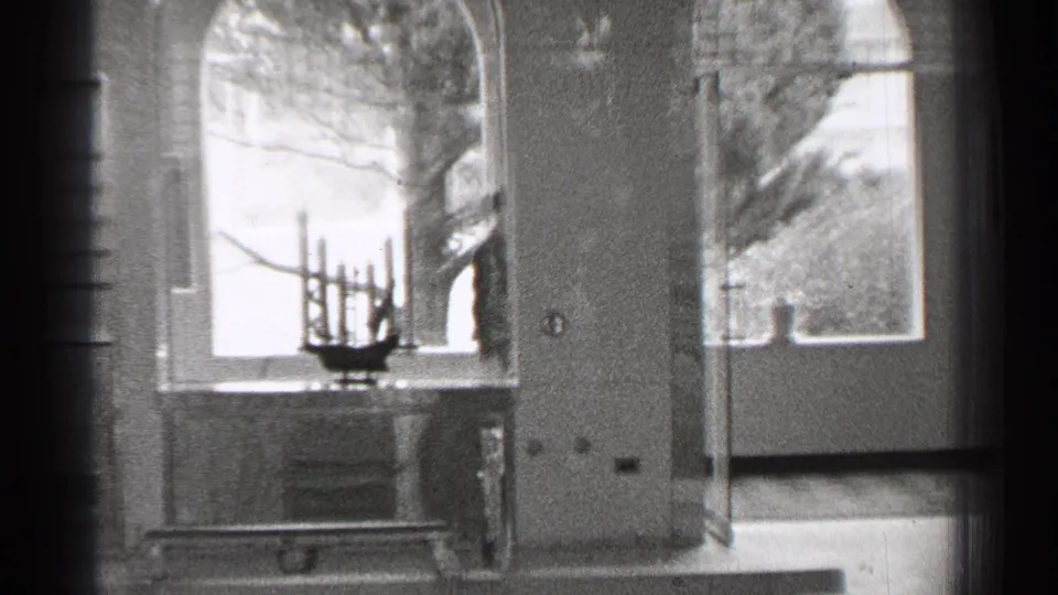 The final frame holds on a window ledge with a candelabra-like object, shutters, doorway, and trees outside.