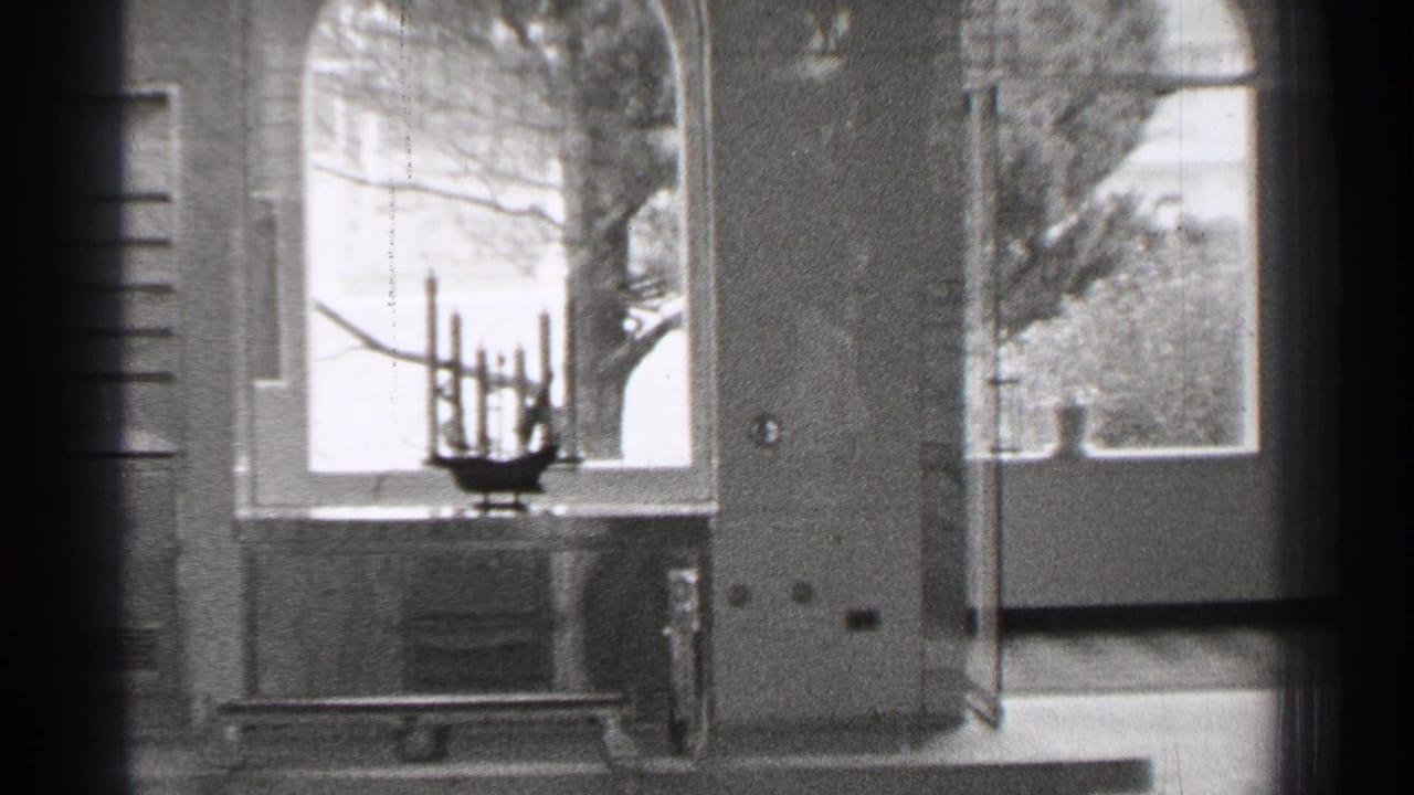 Empty hospital ward corner with a metal bed, large windows, and a small fixture near the sill.