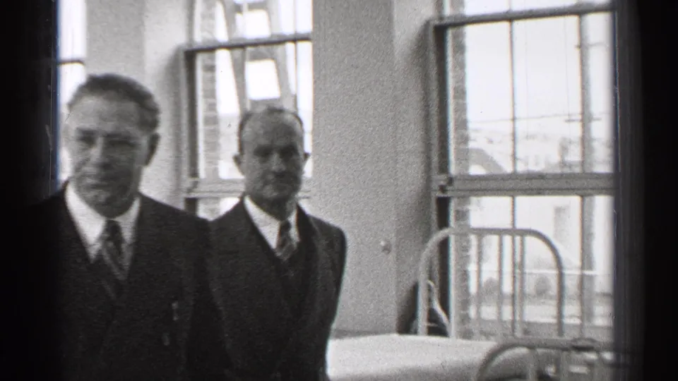 Near the end of the clip, the suited men pass closer to the camera inside the 1944 San Francisco hospital ward.