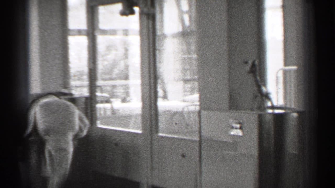 1944 San Francisco home-movie frame showing a small child or young figure near tall interior windows in a private residence.