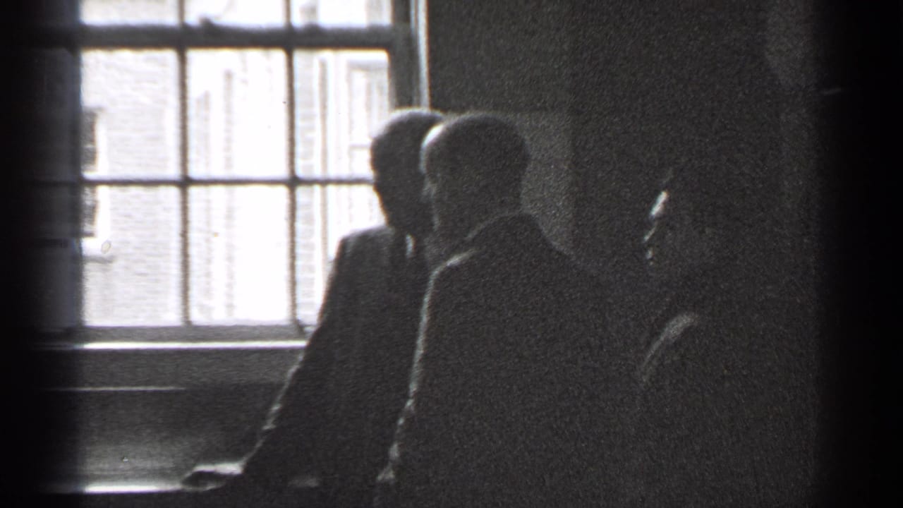 Shadowed adults standing or seated near a bright multi-pane window.