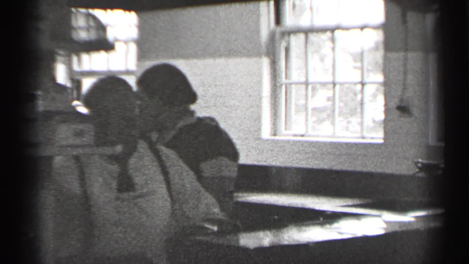 Two women in aprons work at a counter in a San Francisco kitchen-like interior, filmed in black-and-white 8mm around 1944.