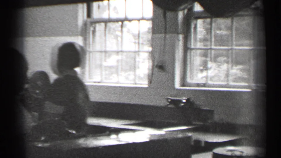 A woman in an apron stands by a counter in the same 1944 San Francisco kitchen-like interior, silhouetted against bright windows.