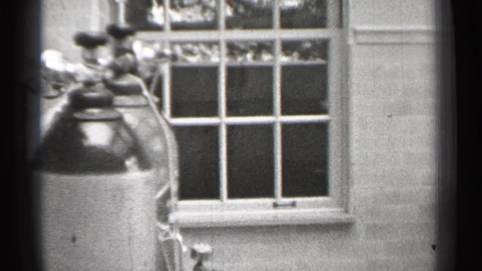 1944 San Francisco 8mm frame showing oxygen tanks near a multi-pane window in a plain clinical or institutional interior.