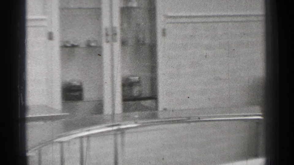 1944 San Francisco 8mm frame showing a door, paneled wall, and part of a window in a sparse institutional interior.