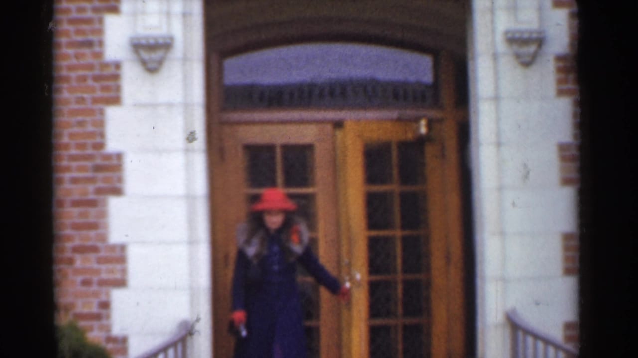 Woman in a red hat opening a wooden glass door at a brick and stone entry.