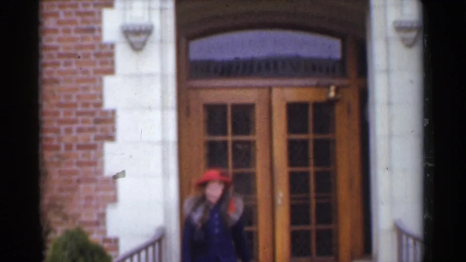 A woman in a red hat and fur-collared coat appears outside a San Francisco residential doorway in 1944 home-movie footage.