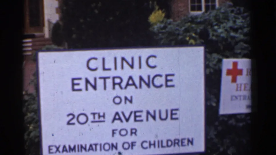 A clinic entrance sign on 20th Avenue is shown beside shrubs and a partial Red Cross-style sign.