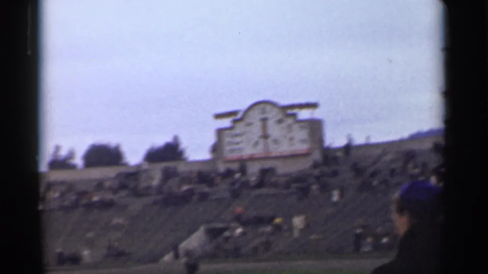 1944 San Francisco frame showing stadium seating, scattered spectators, distant hills, and a scoreboard-like structure.
